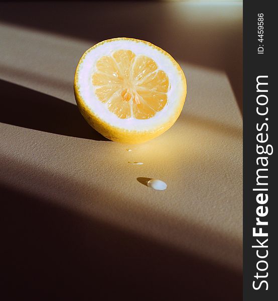 A lemon and a drop with a warm lateral light that emphasizes shadows. Different from usual lemon shots. A lemon and a drop with a warm lateral light that emphasizes shadows. Different from usual lemon shots