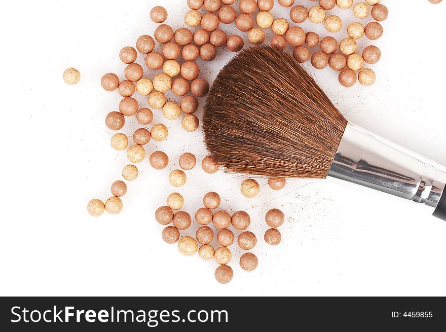 Bronzing pearls and thick brush on white background
