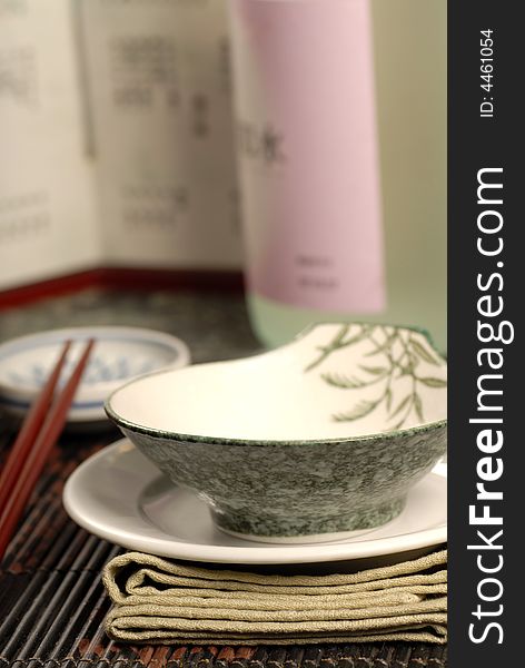 Asian restaurant table setup with sake bottle in background. Asian restaurant table setup with sake bottle in background