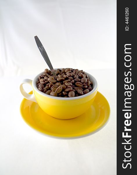 Yellow cup of coffee seeds