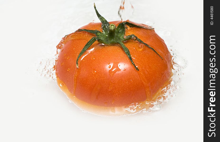 Tomato is being sunken into the water while being washed. Tomato is being sunken into the water while being washed