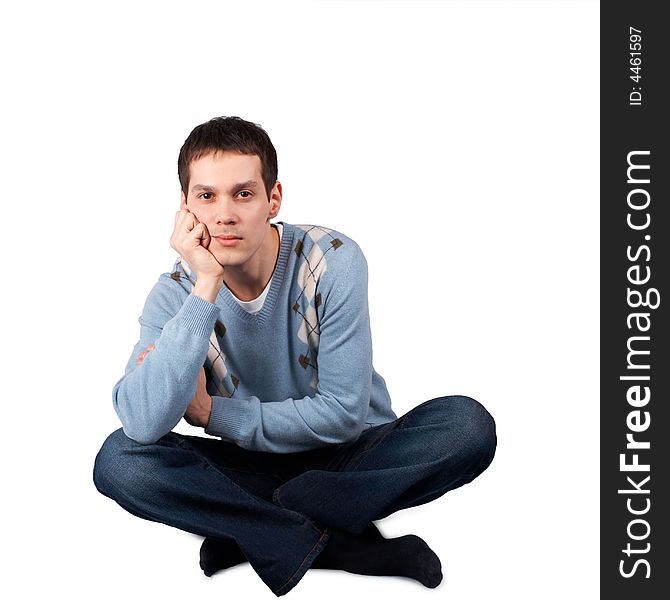 Young man sits on floor, isolated on white