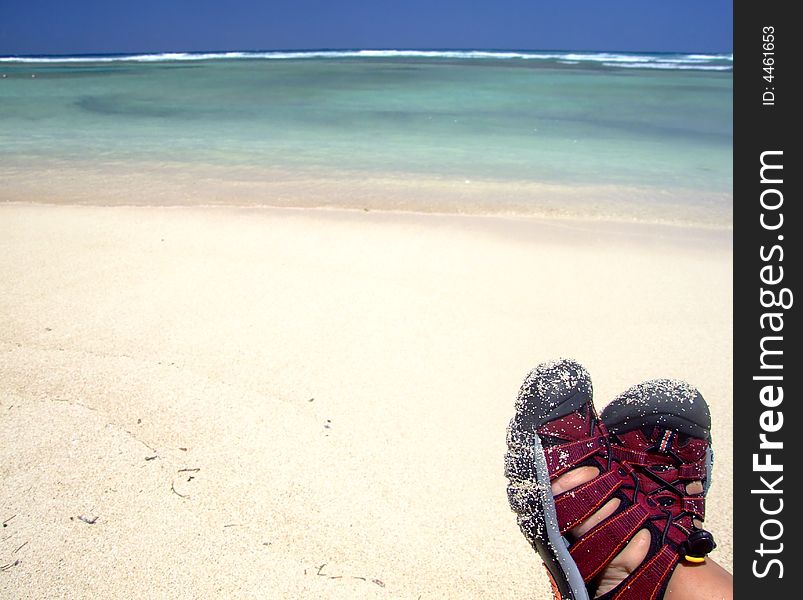 Person wearing red sandals enjoying tropical, sandy beach.  Feet visible only. Person wearing red sandals enjoying tropical, sandy beach.  Feet visible only.