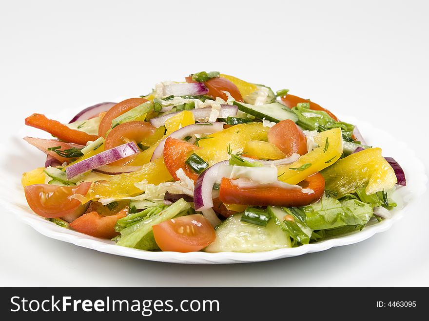 Salad from fresh vegetables on a white plate on a white background