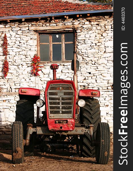 Old red tractor in front of an old country house