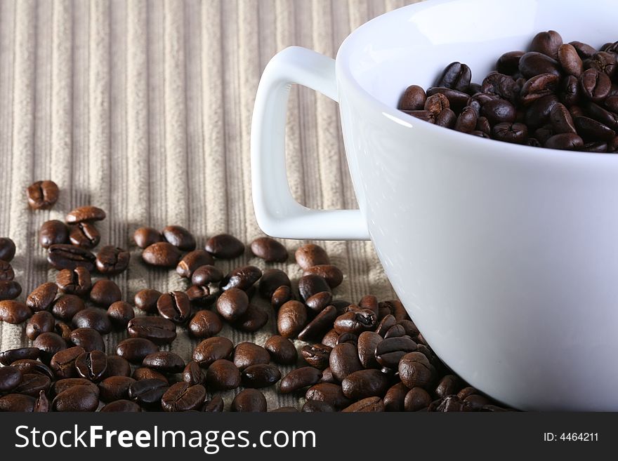 Coffee cup full of coffee beans on textured background