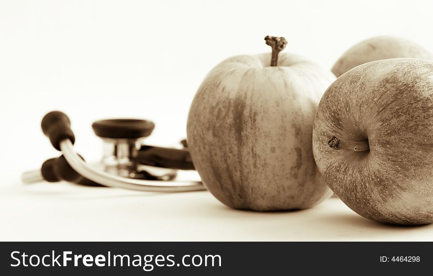 Still life of three apples and an out of focus stethoscope suggesting apples keeping away the doctor. Still life of three apples and an out of focus stethoscope suggesting apples keeping away the doctor.