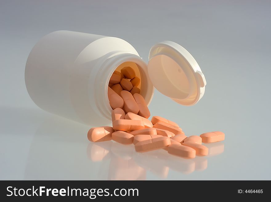 Medicine pills with a white bottle on a grey background. Close-up