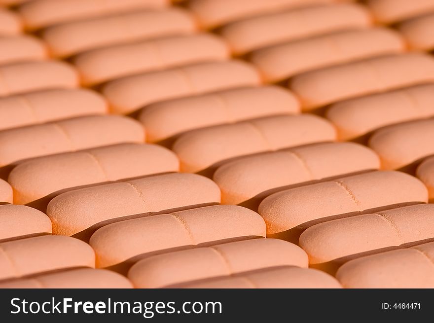 Rows of pink pills over white. Macro. Close-up