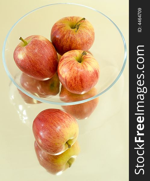 Still life of apples in a shallow glass bowl on a reflective surface. Still life of apples in a shallow glass bowl on a reflective surface