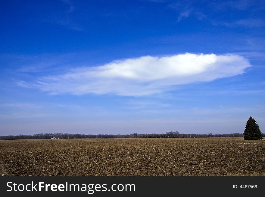 Winter cold day countryside vista with heavy browns fields and floating cloud in brith blue sky. Winter cold day countryside vista with heavy browns fields and floating cloud in brith blue sky