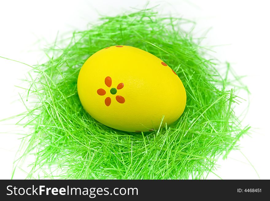 One yellow easter egg with green grass isolated on white