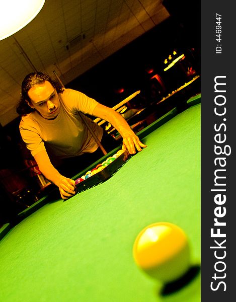 A female pool player bending over the green table and ready to hit the white ball.