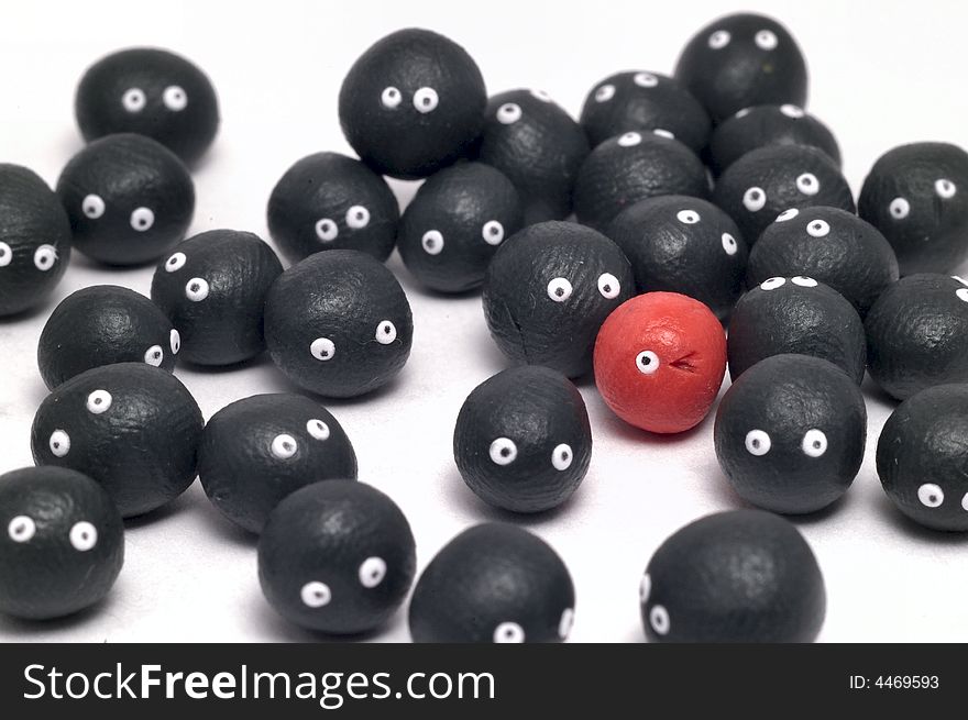 The idea of being different, distinguished among the others. Little plasticine balls with eyes. The red one is winking. White background. The idea of being different, distinguished among the others. Little plasticine balls with eyes. The red one is winking. White background.