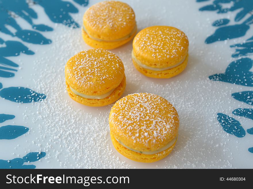 Four yellow macarons with a lemon-mint-filling on blue and white background. Four yellow macarons with a lemon-mint-filling on blue and white background