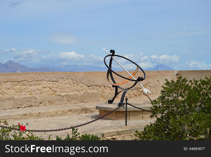 An unusual steel sundial with its arrow pointing towards the distant mountains. An unusual steel sundial with its arrow pointing towards the distant mountains.