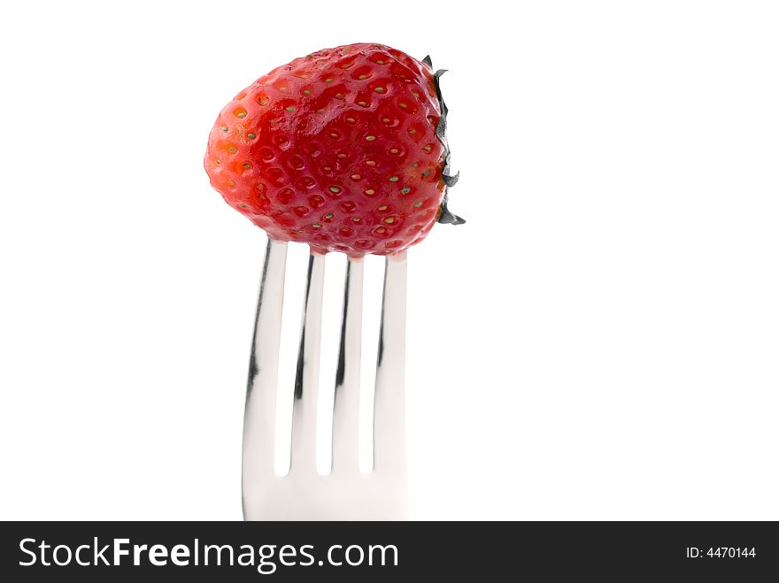 A fresh red strawberry on a fork against a white background. A fresh red strawberry on a fork against a white background