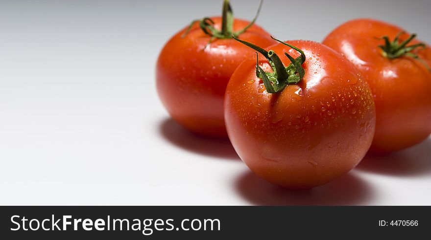 Three tomatoes on a light background