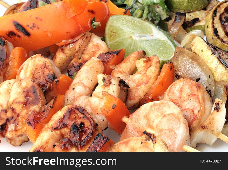 Grilled prawns on bamboo sticks served with salad and grilled vegetables in dinner setting.