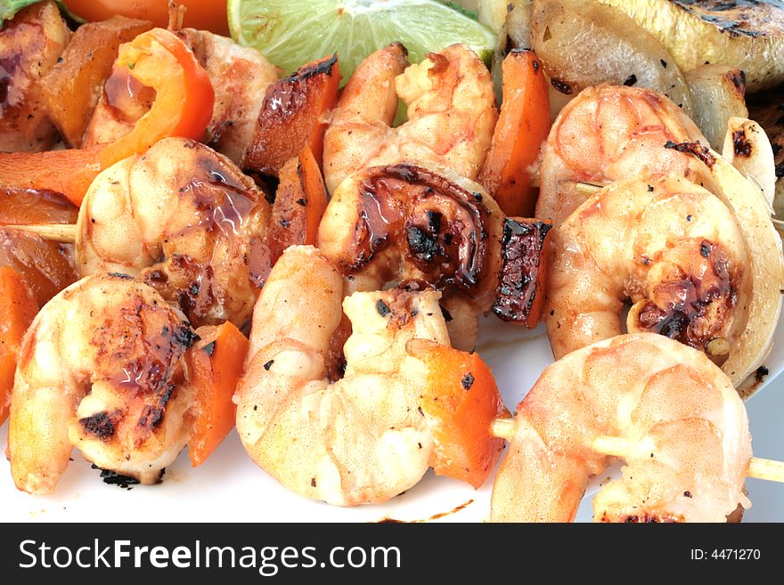 Grilled prawns on bamboo sticks served with salad and grilled vegetables in dinner setting.