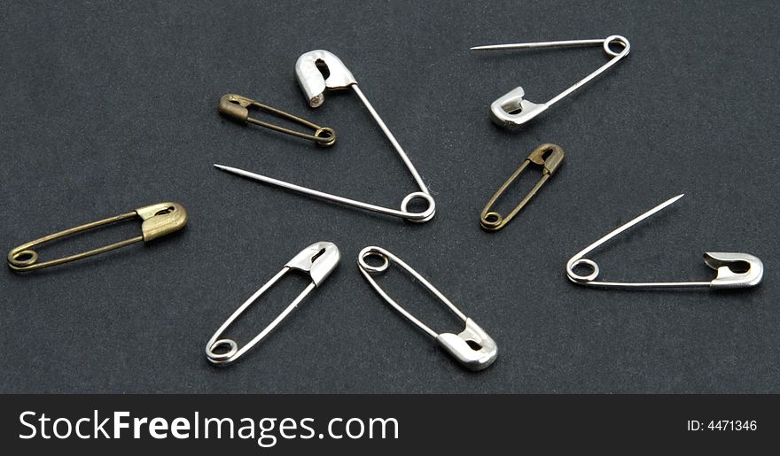 Old vintage safety pins stainless and brass on black background