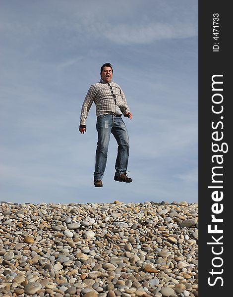 Young casual man jumping at the beach