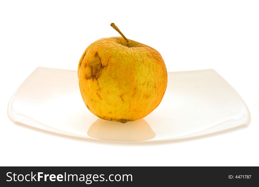 Isolated withering apple lying on the white dish