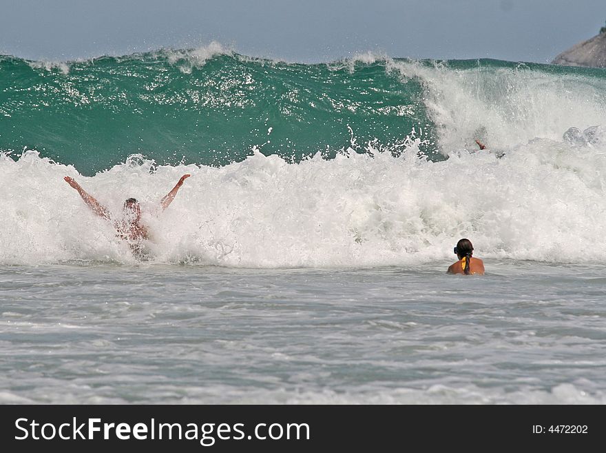 Two tourists enjoy the large waves on a Thai tropical beach