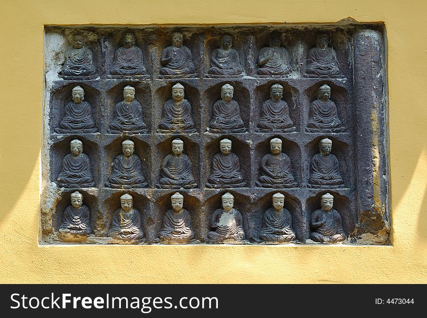 Many buddhist sculptures on the wall.