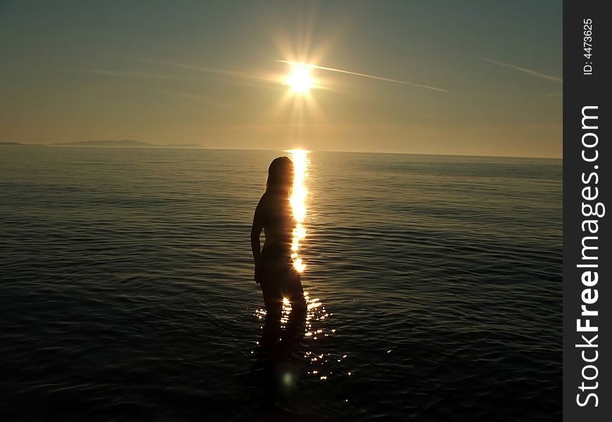 Woman silhouette against sunset in the sea