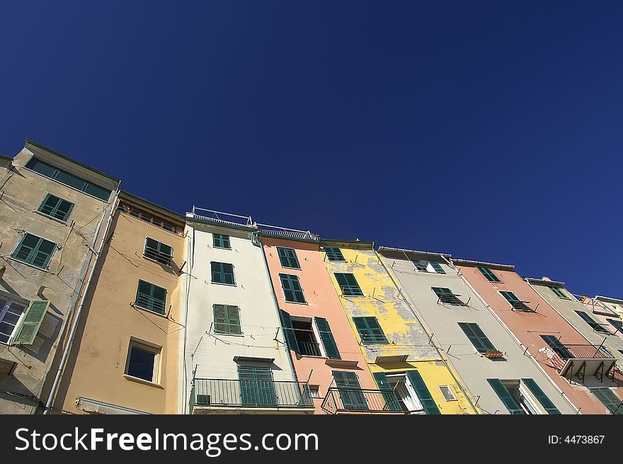 Front view of the colorful and old facades in a touristic italian port. Empty blue sky for copy space.