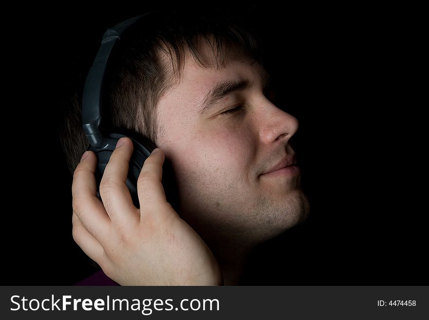 Attractive men listening music in headphones on black background