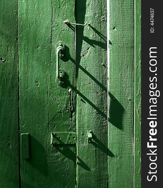 The door with bolts and a hook is green. The door with bolts and a hook is green