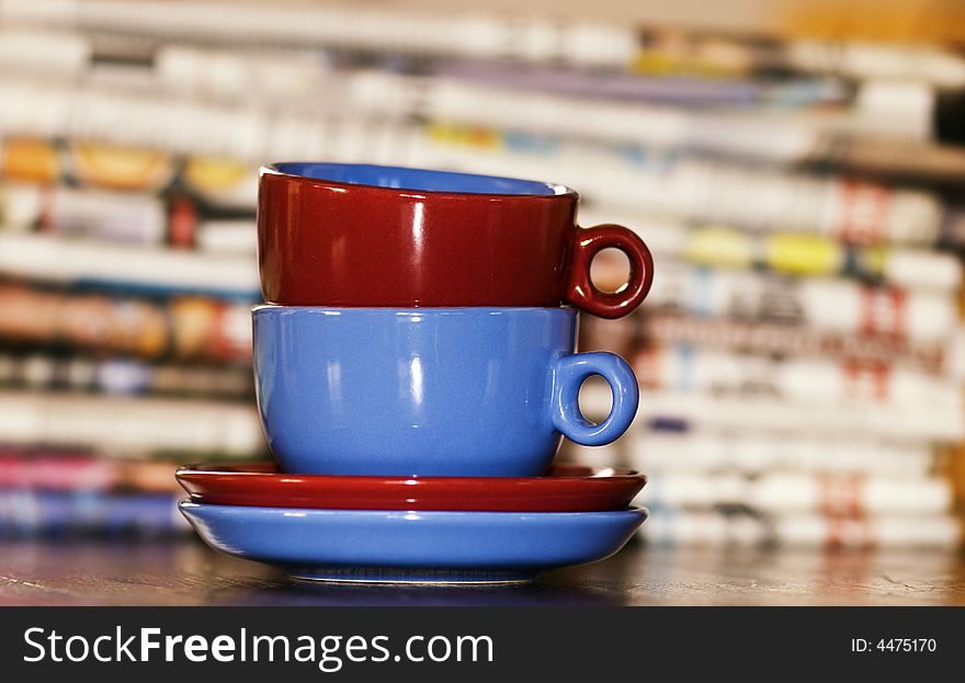 Vivid colored cups against a stck of newspapers. Vivid colored cups against a stck of newspapers