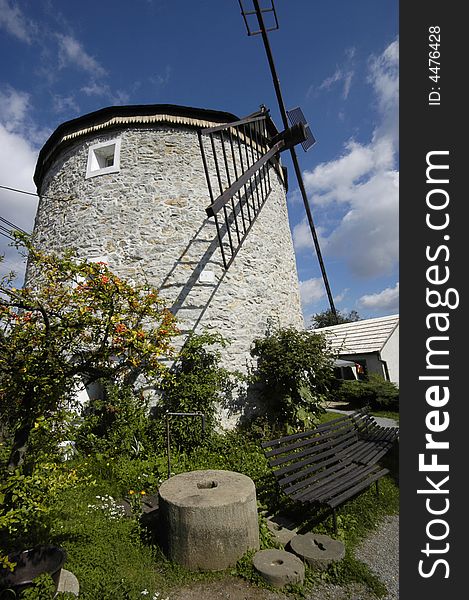 Mill stones and benches in front of ancient wind mill in a small village called Rudice. The village is situated in national park Moravsky kras in Czech republic. Mill stones and benches in front of ancient wind mill in a small village called Rudice. The village is situated in national park Moravsky kras in Czech republic