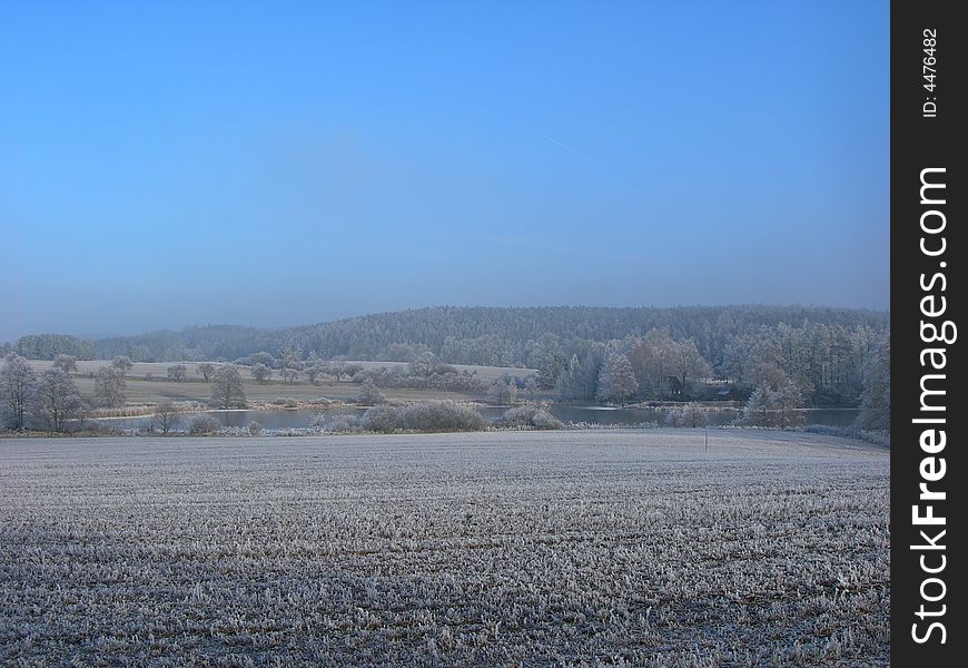 Field and forest covered with snow in winter in misty atmosphere. Field and forest covered with snow in winter in misty atmosphere