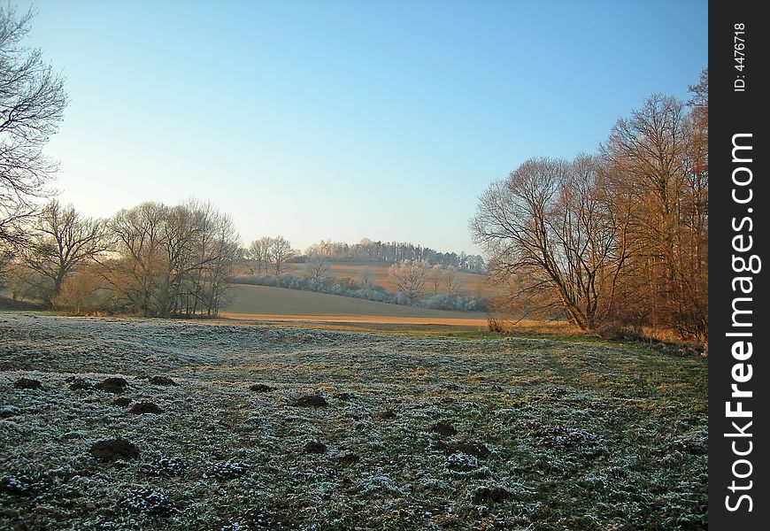 Ploughed field and forest covered with snow in winter in misty atmosphere. Ploughed field and forest covered with snow in winter in misty atmosphere