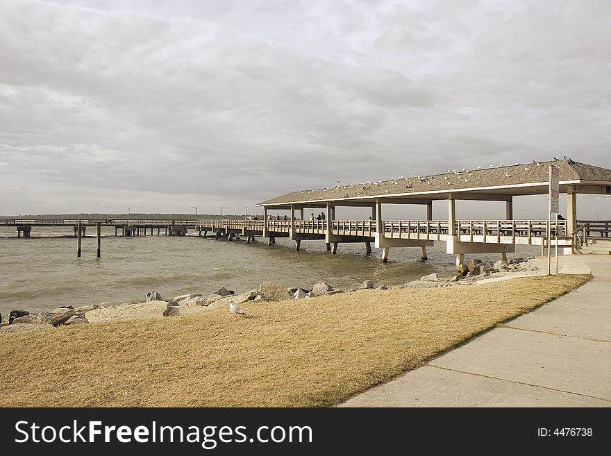 A pier on a rocky beach on a cloudy winter day. A pier on a rocky beach on a cloudy winter day