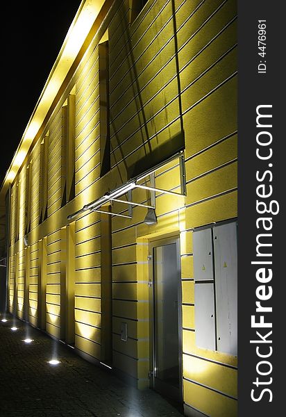 Yellow building at night with lights up toward