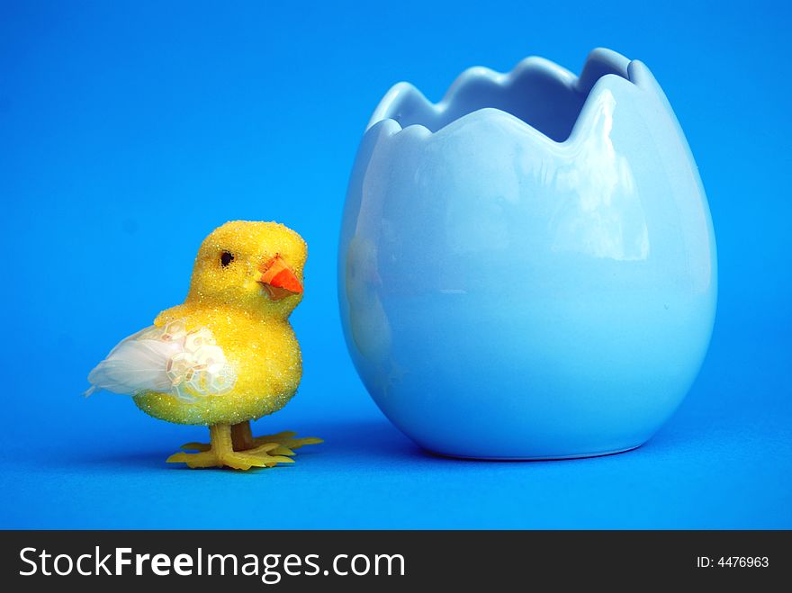 An easter toy chick with a blue egg shell with blue background. An easter toy chick with a blue egg shell with blue background