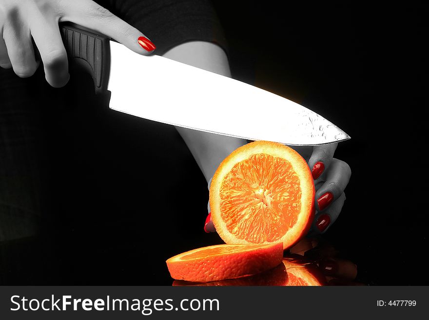 Woman is chopping orange on the black background. Woman is chopping orange on the black background