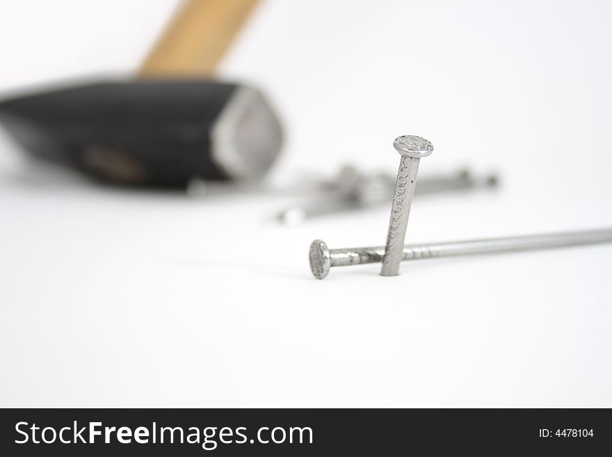 Few white nails on light background with standing hammer. Few white nails on light background with standing hammer