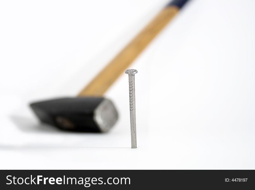 Driven-in nail and hammer on white background
