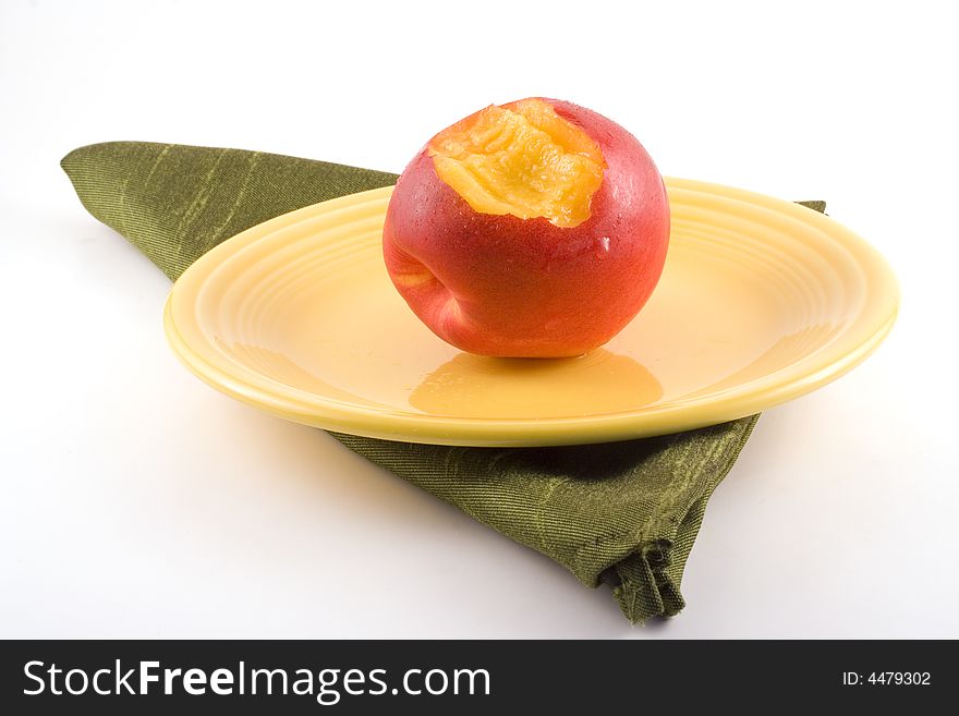 A nectarine with a bite out of it sits on a yellow plate. A nectarine with a bite out of it sits on a yellow plate.
