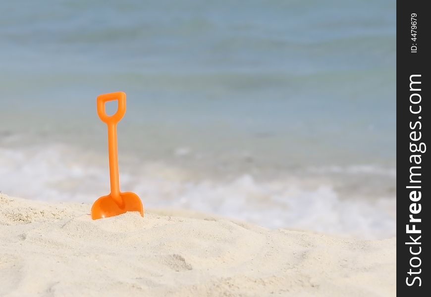 Red plastic spade on the sunny tropical beach