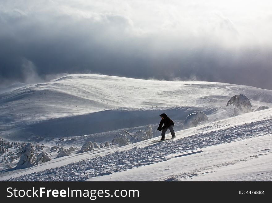 Snowboarder freeride via mountain peak and storm