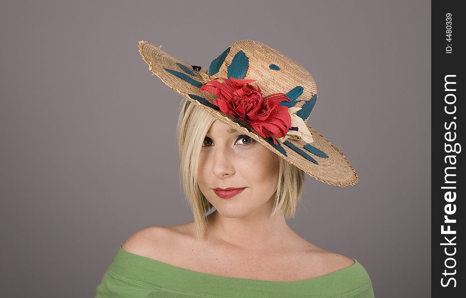 A blonde in a flowered straw hat pulled low over one eye. A blonde in a flowered straw hat pulled low over one eye