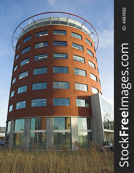 Modern round-shaped office building made of red brick and glass in Hoogvliet, Holland