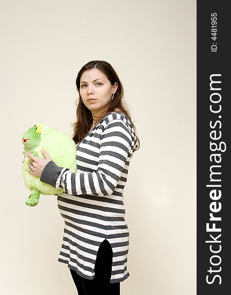 Happy pregnant young woman holding frog doll. Happy pregnant young woman holding frog doll
