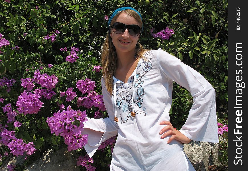 There is a beautiful girl next to the bush of bougainvillea. There is a beautiful girl next to the bush of bougainvillea